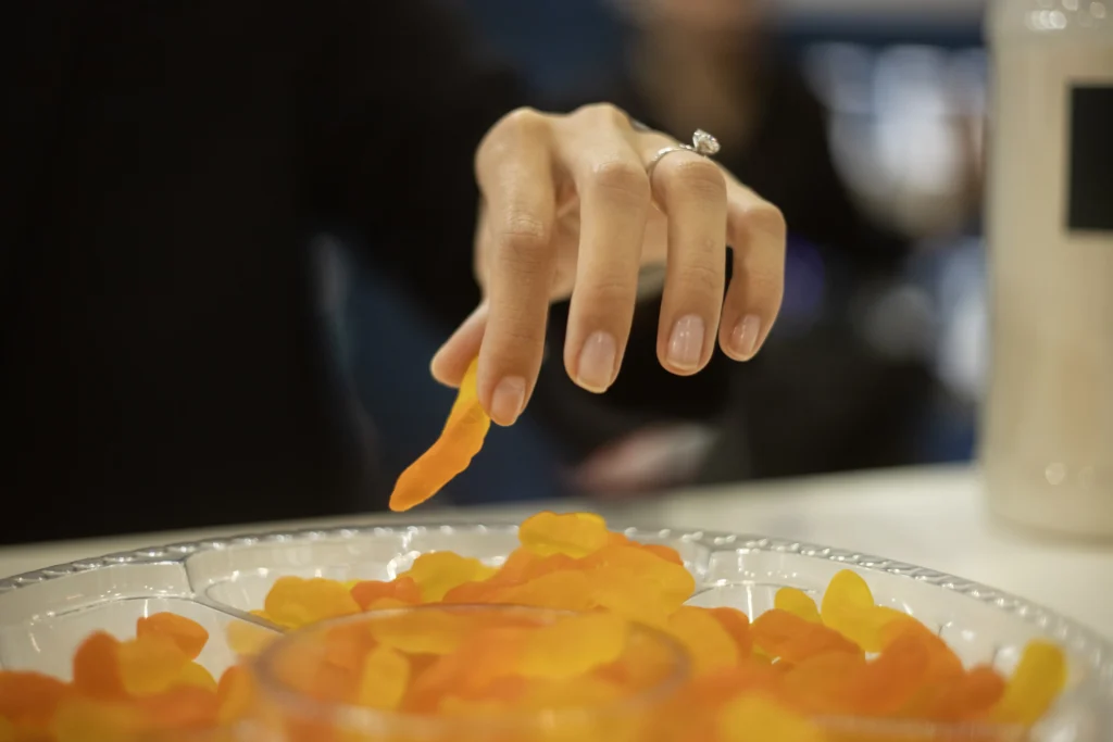mano tomando gomita, ingredientes para confitería, jaleas y caramelos de goma